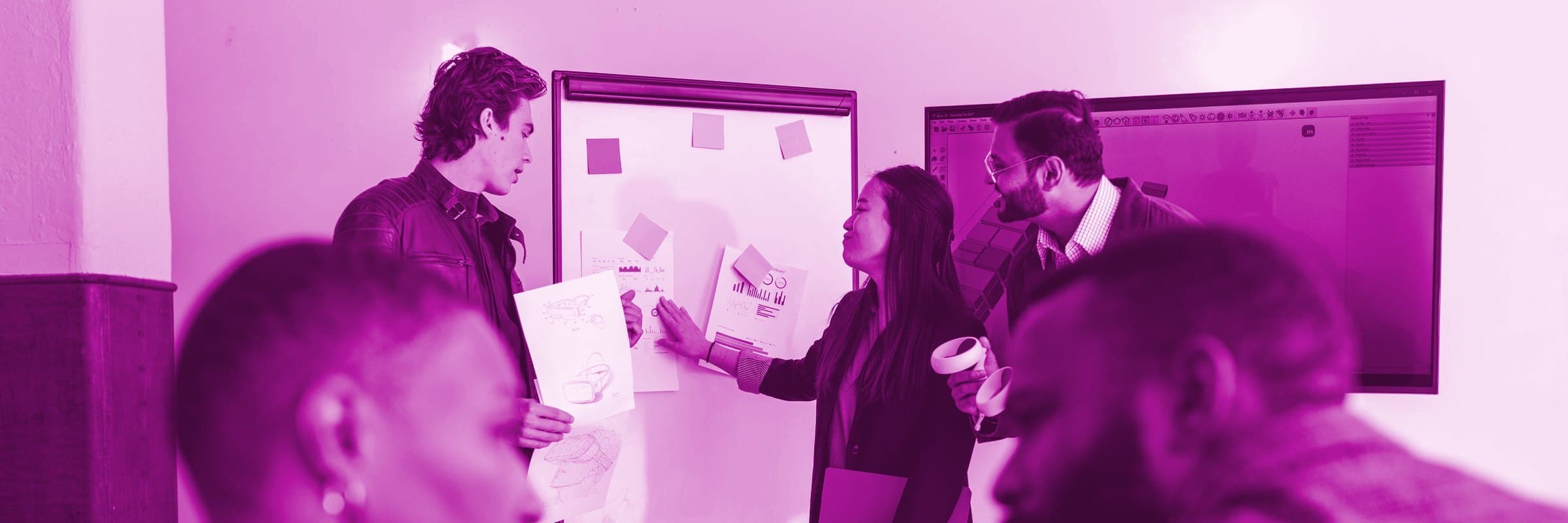 A small group talking through sticky notes and sketches on a whiteboard