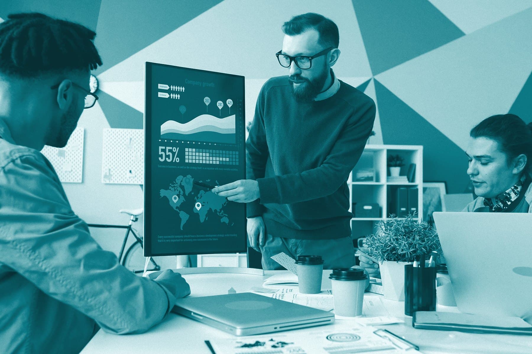 A small team at a table while one person points to a growth chart on a standing screen