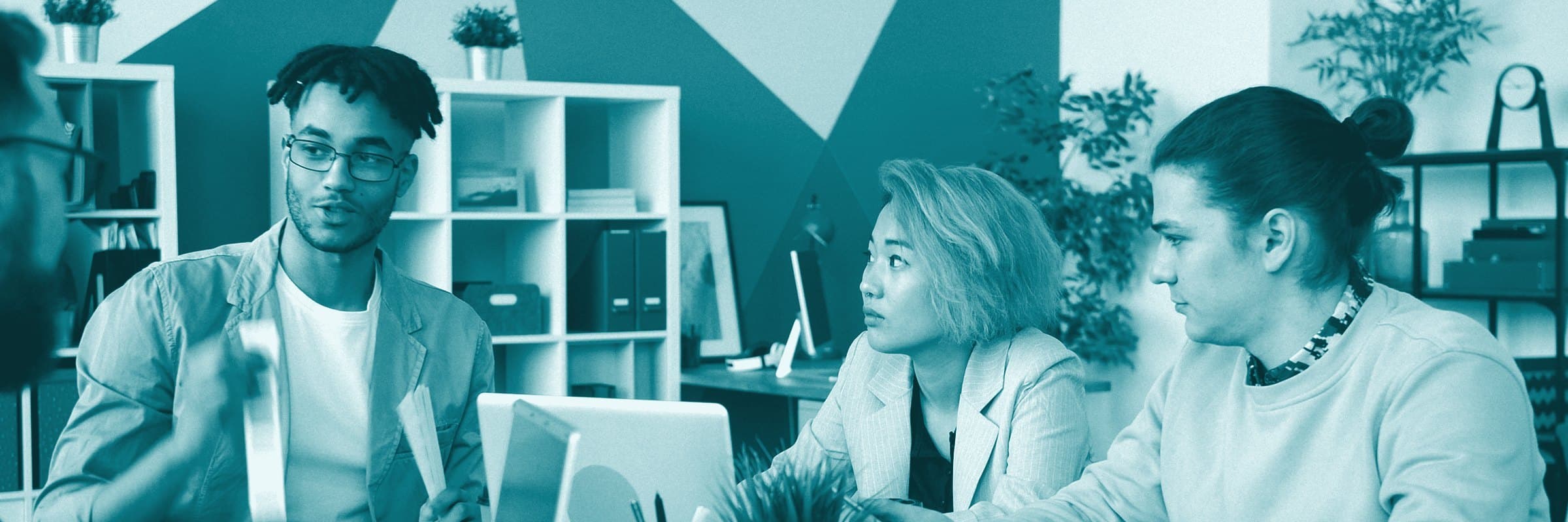 Three colleagues talking around a laptop in a bright office